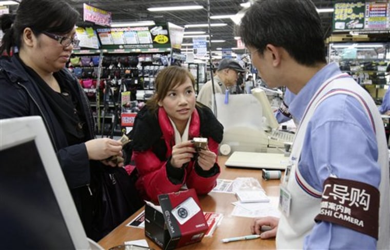 Chinese customers speak with a salesclerk as they buy a compact digital camera at Yodobashi Camera in Tokyo's Akihabara electronics district. For years, Japanese auto and electronics companies have been expanding in China as its economy boomed to offset slow growth at home. 